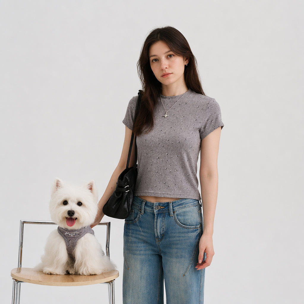 Woman wearing a gray speckled cropped tee standing beside a white small dog in a matching gray dog shirt, featuring soft dog apparel and pet parent matching clothes.