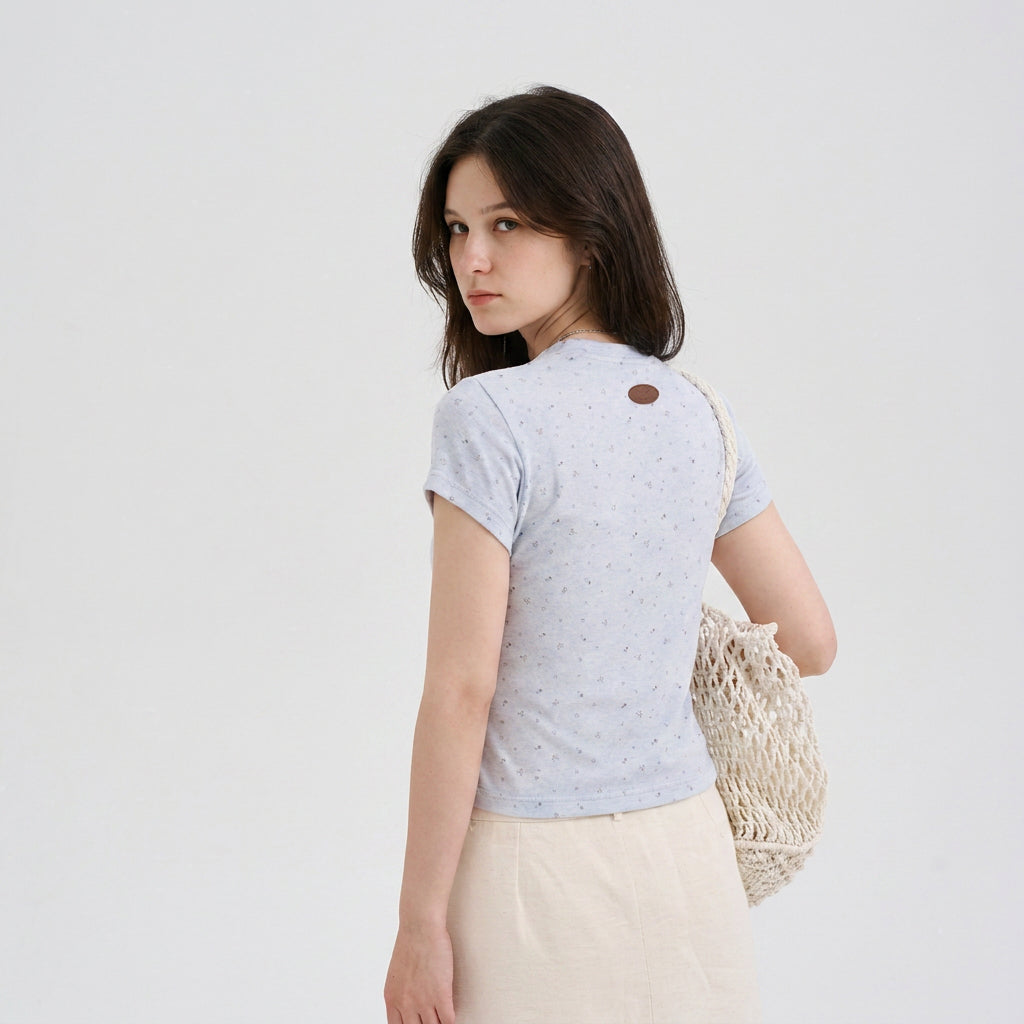 Back view of a woman wearing a light blue speckled pet parent tee with a cropped fit and logo patch, designed as the owner top for matching pet and owner apparel.