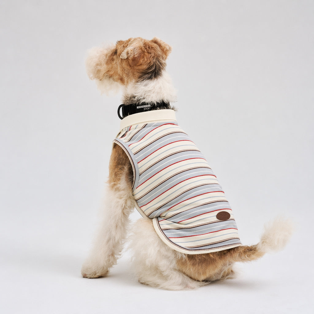 Tan and white terrier shown from the back wearing a striped sleeveless dog polo shirt with a white collar and curved hem, featuring casual dog apparel for small pets.