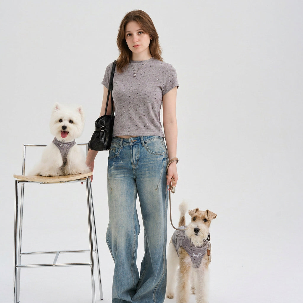 Woman wearing a gray speckled cropped tee standing with two small dogs in coordinated gray dog shirts, featuring casual dog apparel and pet parent matching clothes for everyday style.