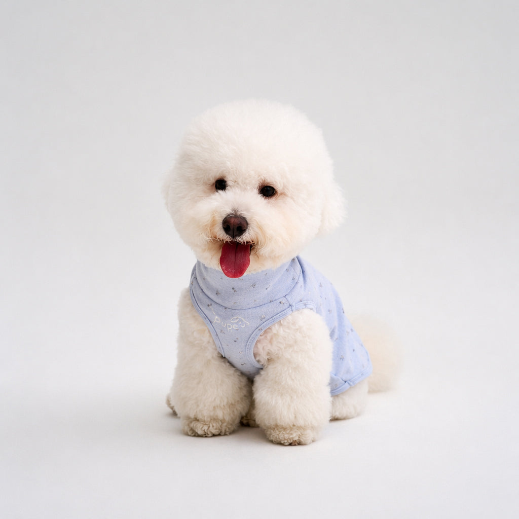 Fluffy white small dog sitting in a light blue speckled dog tee, featuring soft dog apparel and comfortable small dog clothes for everyday pet clothing style.