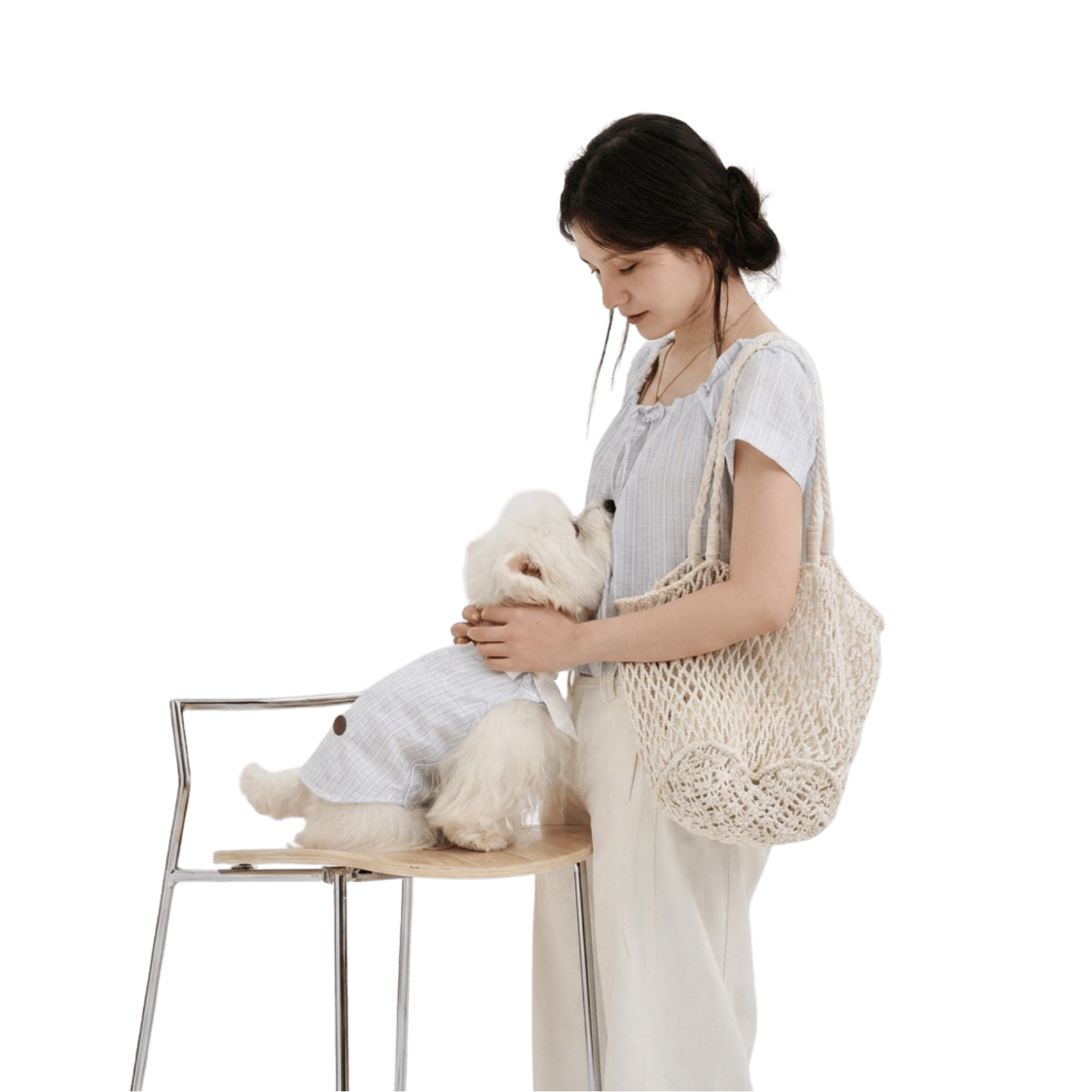 Pet parent wearing a light blue striped top gently interacting with a white small dog in a matching dog shirt, featuring soft pet apparel for everyday bonding moments.