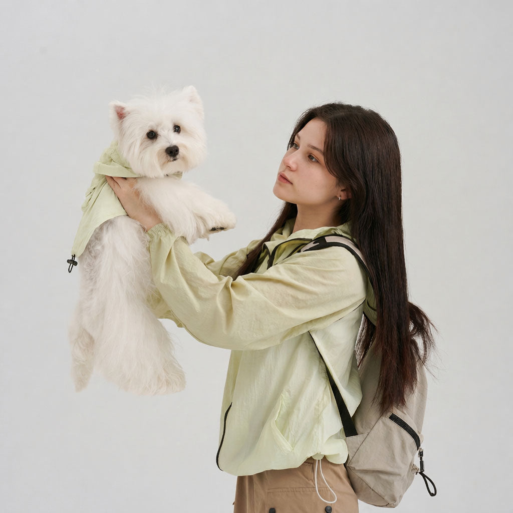 Pet parent wearing a pale green sun protection jacket while holding a white small dog in a matching pale green dog sun jacket, featuring lightweight dog apparel and a soft pet parent matching outfit.
