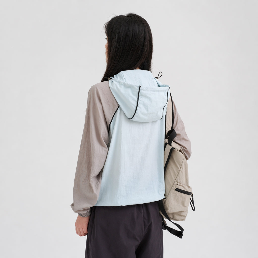 Back view of a pet parent wearing a light blue and gray hooded sun protection jacket, featuring lightweight owner outerwear designed to pair with dog sun jackets in a matching pet apparel collection.