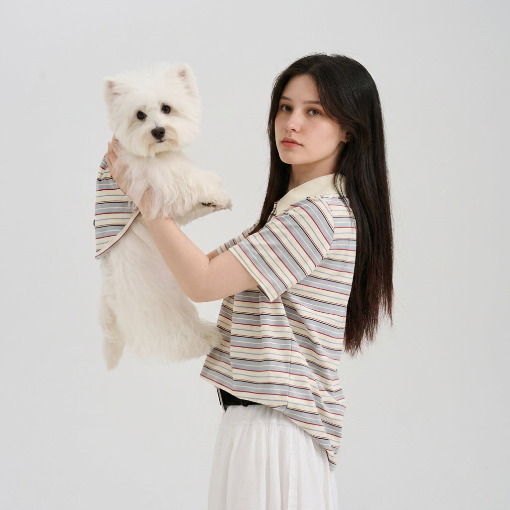 Pet parent wearing a striped short sleeve top while holding a white small dog in a matching striped dog shirt, featuring soft dog apparel and coordinated pet parent matching style.